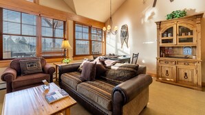 A cozy living room with a sofa, armchair, and a wooden cabinet. - Ski-in/Ski-out Condo Next to Golf Course, Amazing Mountain Views from Balcony (Keystone)