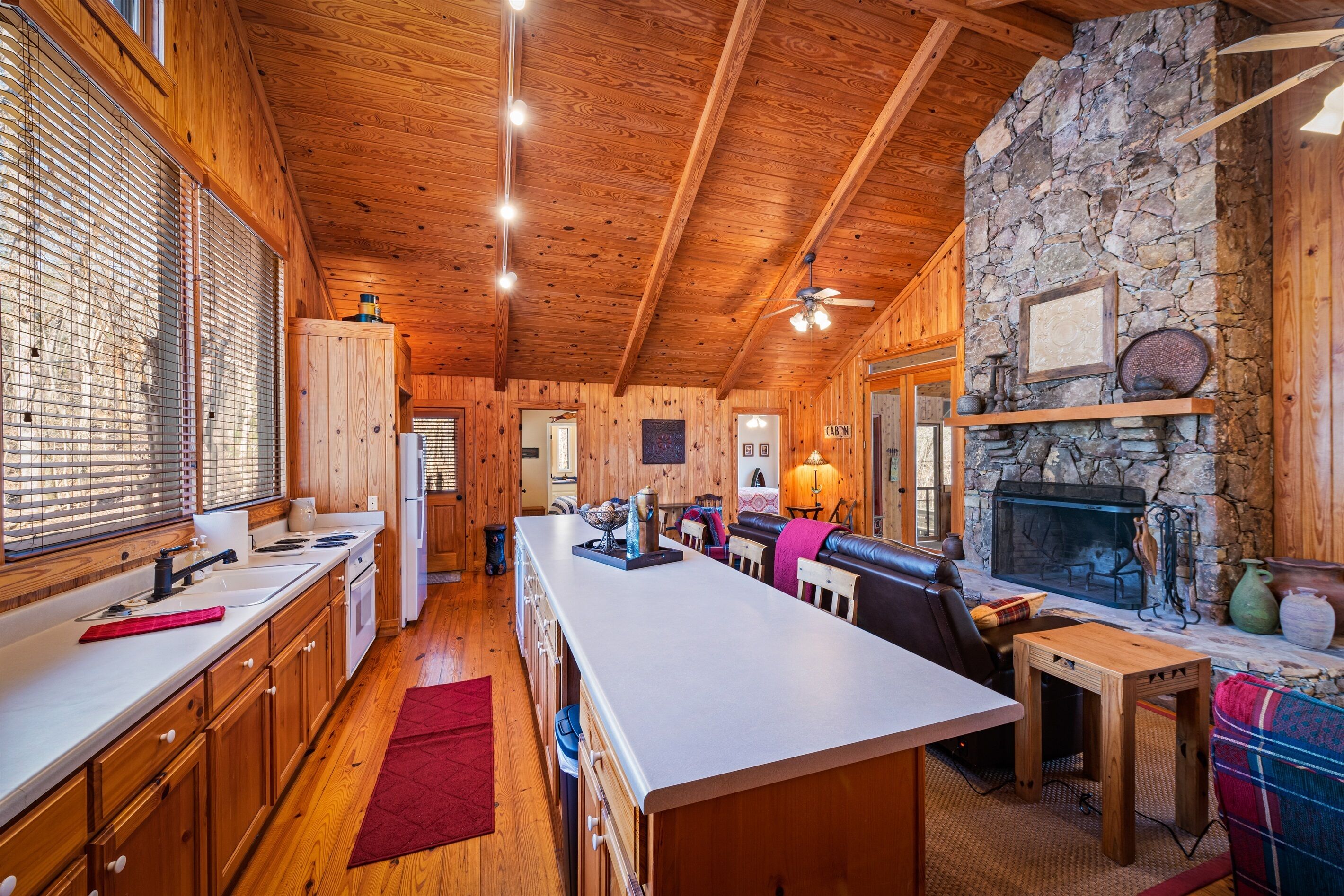 A spacious kitchen with wooden cabinets, a central island, and a stone fireplace.