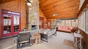 Un acogedor interior de cabaña con chimenea de piedra, techo de madera y una puerta roja.