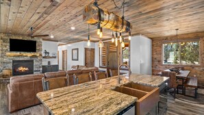 A spacious kitchen with a granite countertop, a built-in sink, and a stone fireplace. - Juniper Mountain Retreat |Hot Tub|Game Room| Views (Orderville)