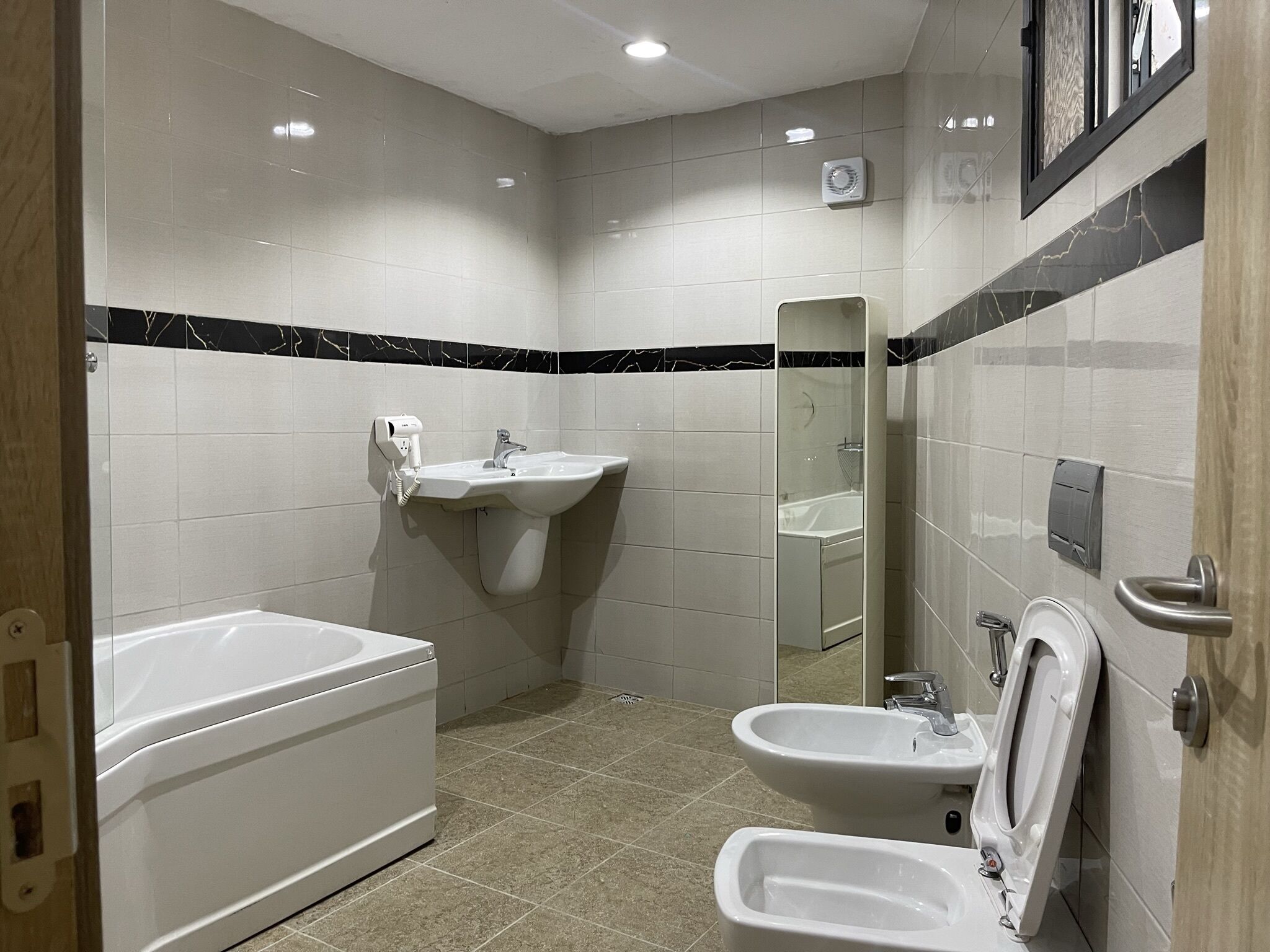 A bathroom with a bathtub, two sinks, a mirror, and a toilet.