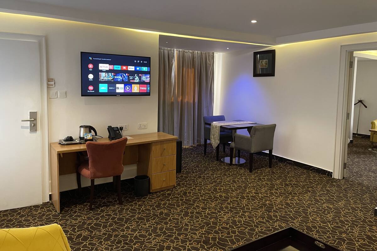 A hotel room with a desk, chair, and a flat-screen TV displaying various streaming services.