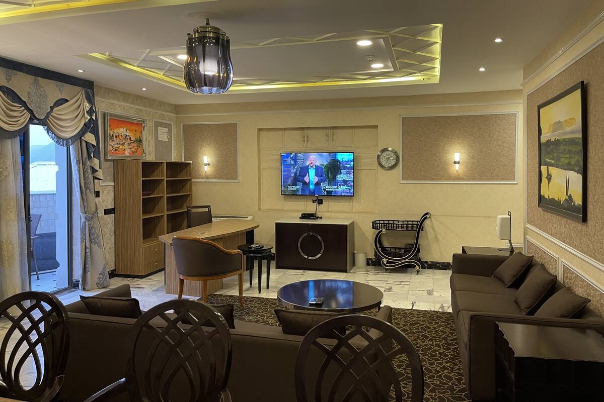 A modern living room with a television, sofa, chairs, and a coffee table.