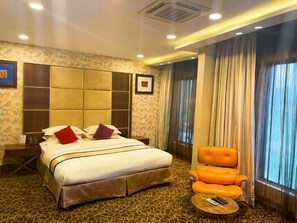 A hotel room with a large bed, a nightstand, a chair, and a small table. - BEST PREMIER MAITAMA RESIDENCE (Abuja)