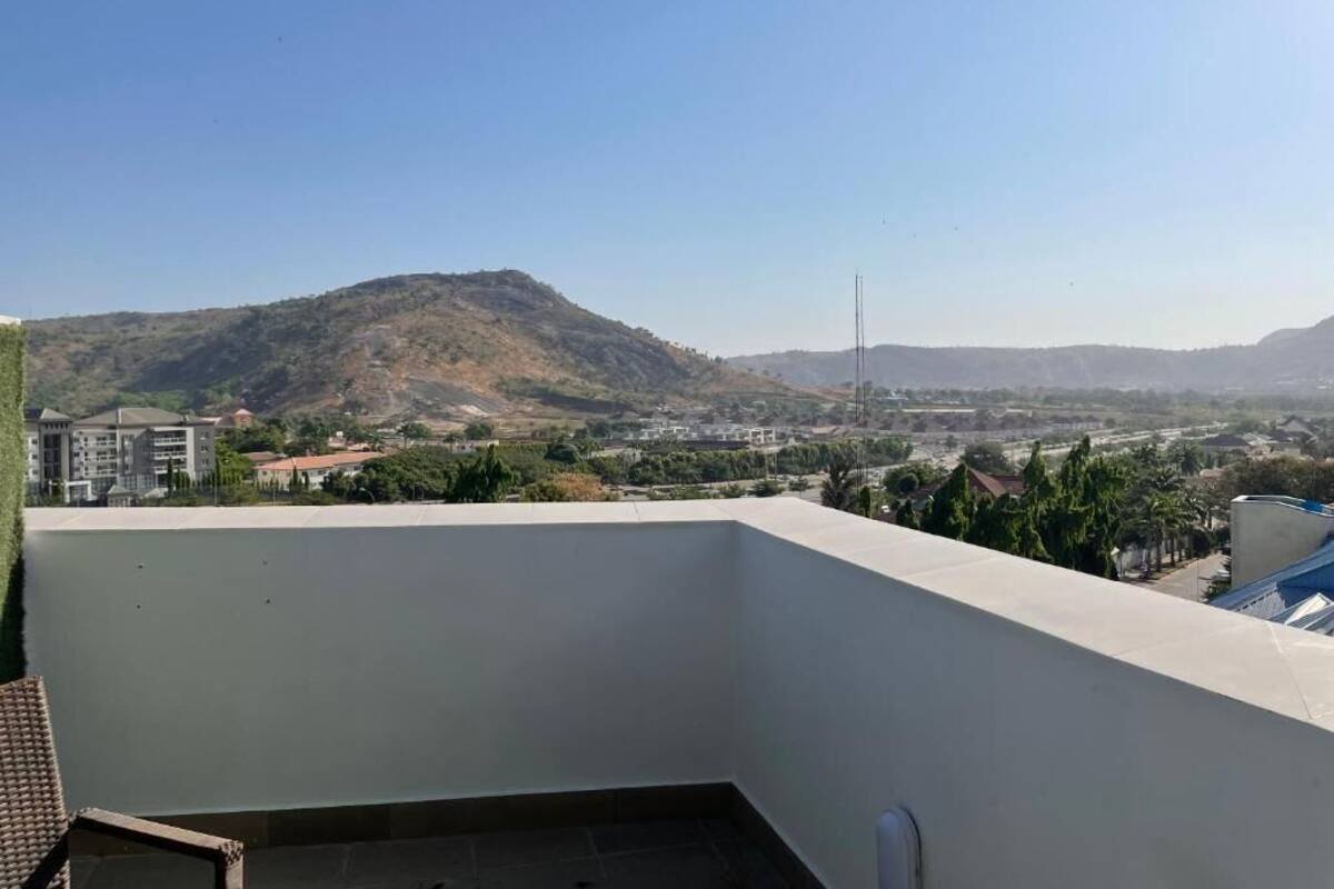 A rooftop terrace with a view of a hilly landscape and distant buildings.