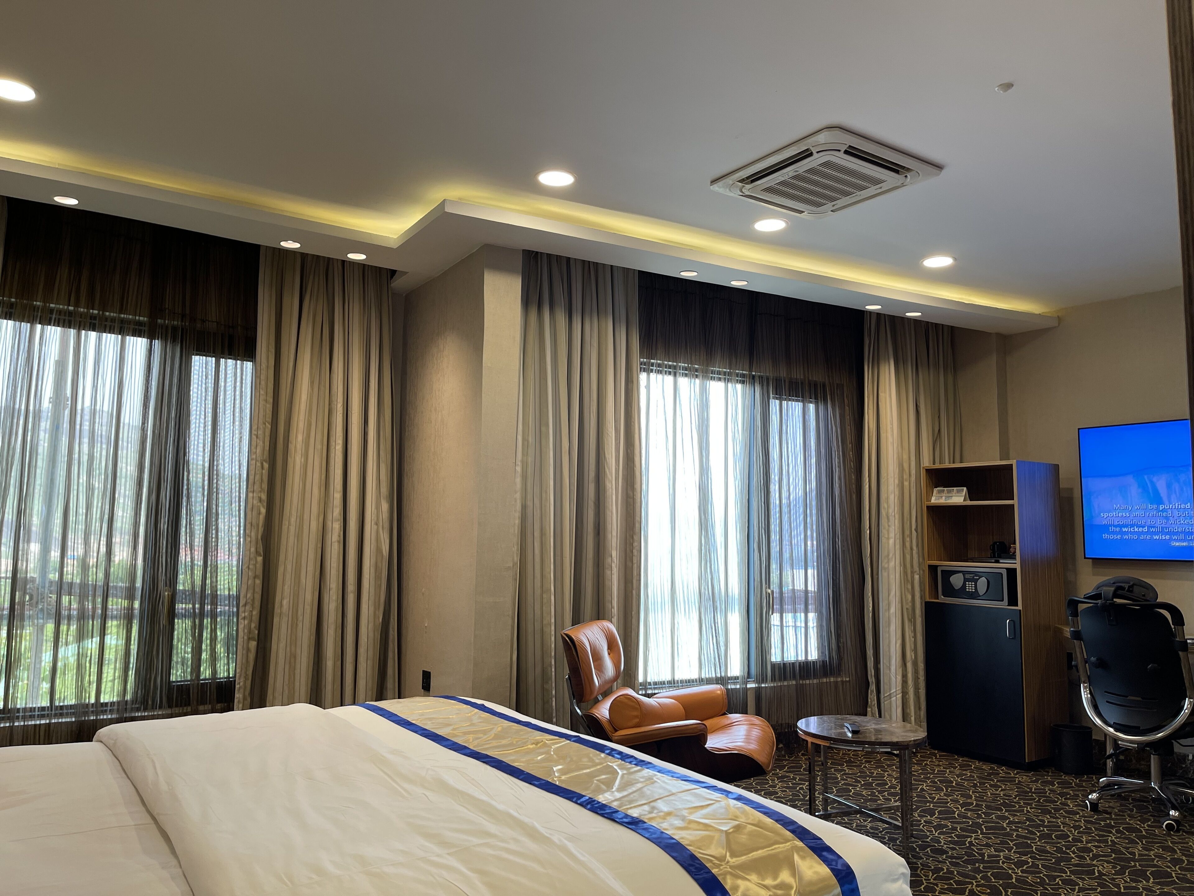 Ein Hotelzimmer mit einem großen Bett, einem Schreibtisch, einem Sessel und einem Fernseher.