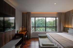 Una camera d'albergo moderna con una grande finestra, un letto, una scrivania e un'area salotto.