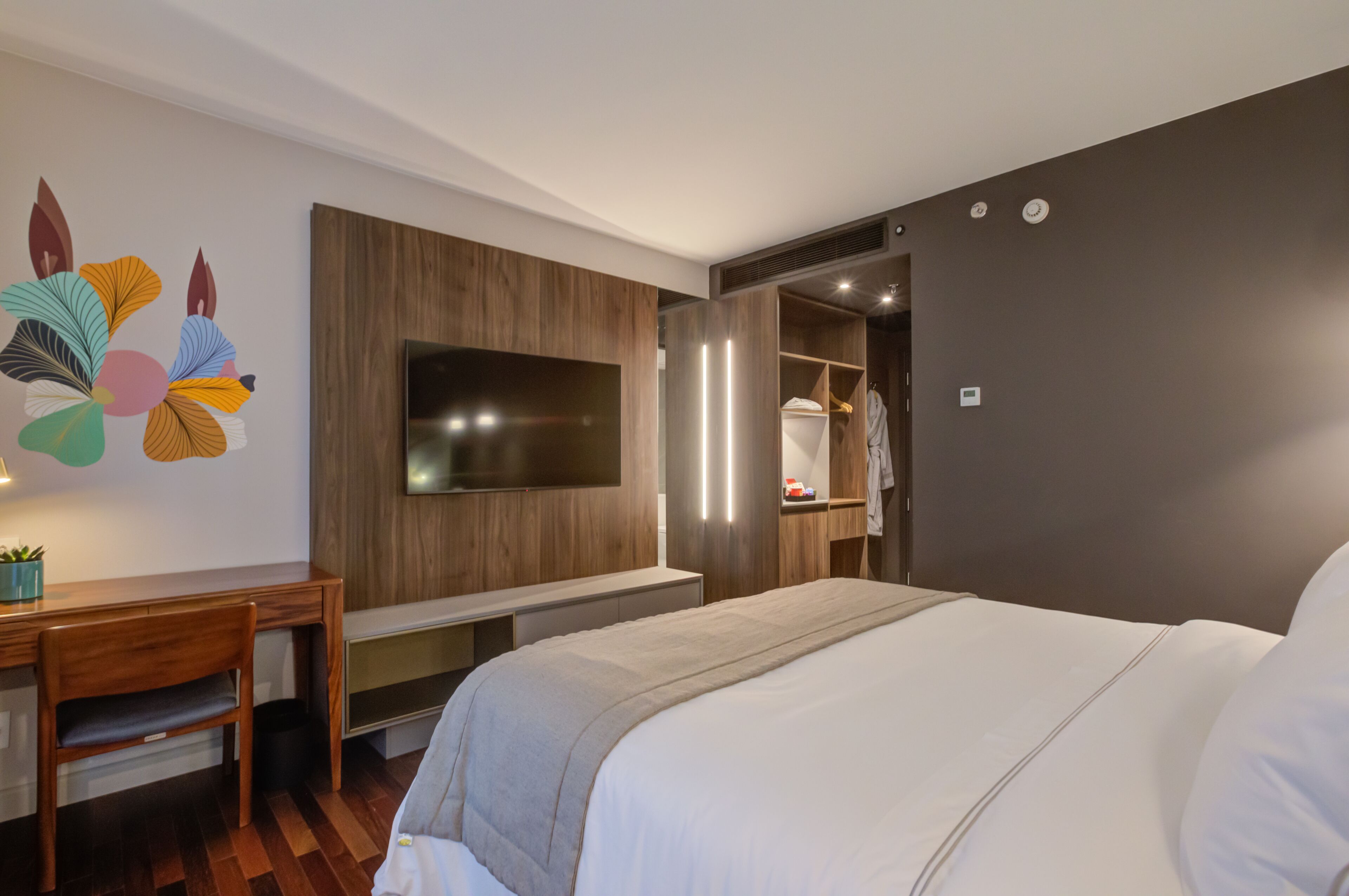 Una moderna camera d'albergo con un letto grande, una scrivania, una TV e un armadio.