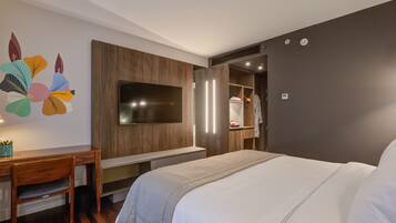 Una moderna camera d'albergo con un letto grande, una scrivania, una TV e un armadio.