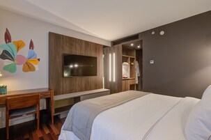 Una moderna camera d'albergo con un letto grande, una scrivania, una TV e un armadio.