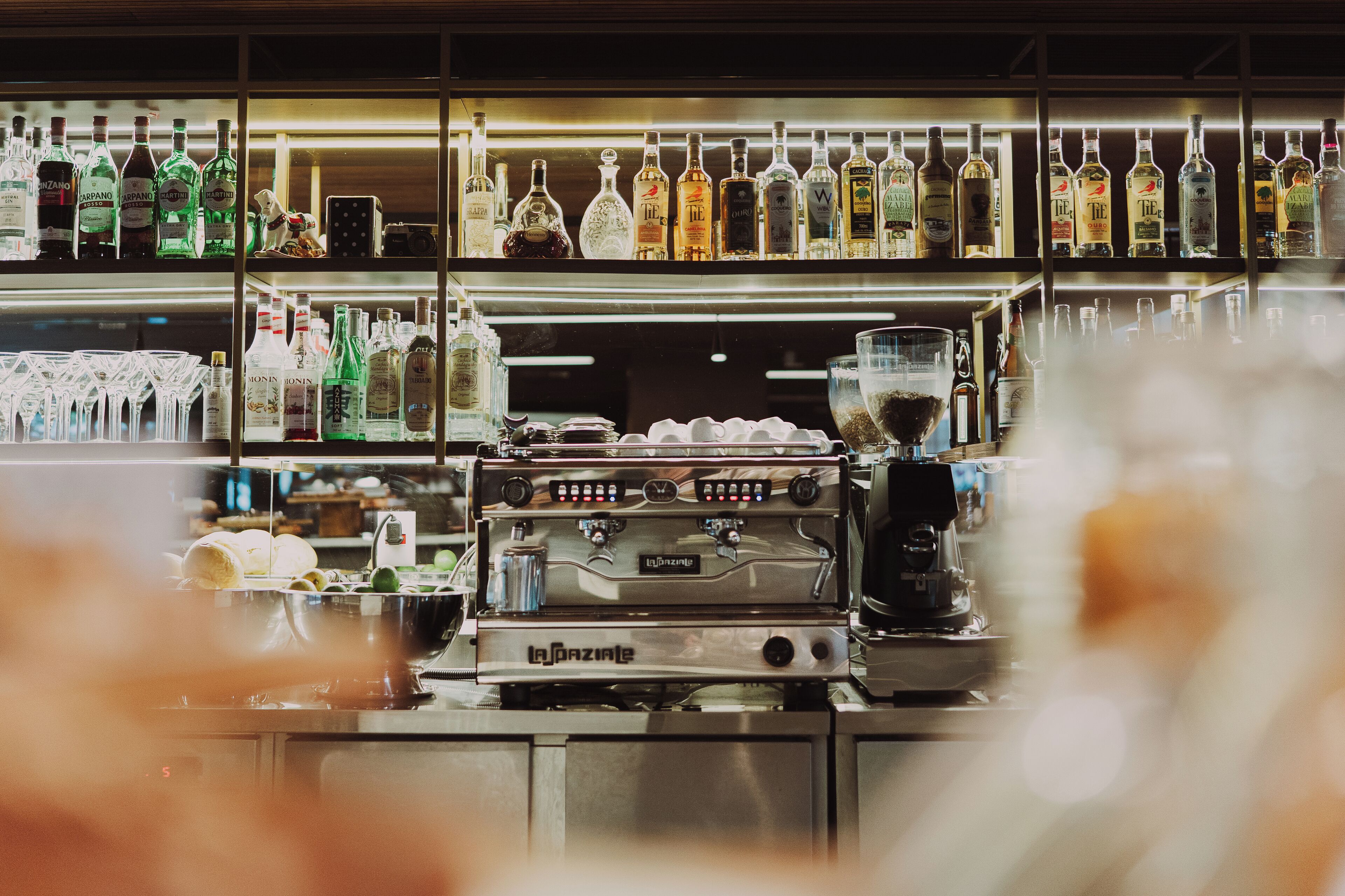A bar area with shelves of liquor bottles and a coffee machine.