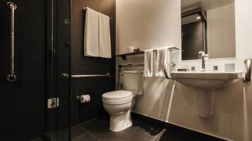A modern bathroom with a glass shower enclosure, a white toilet, and a sink with a mirror above it.