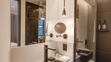 Un baño moderno con un espejo grande, lavamanos dobles y cabina de ducha con mampara de cristal.