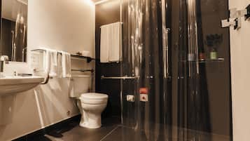 A modern bathroom with a glass-enclosed shower, a toilet, and a sink.