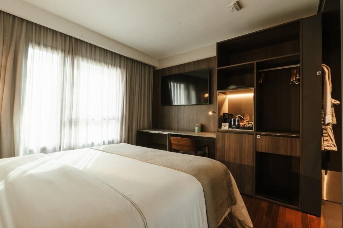 Une chambre d’hôtel avec un grand lit, un bureau, une télévision et une armoire.