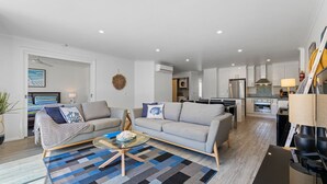 A modern living room with a grey sofa, a round glass coffee table, and a patterned rug.