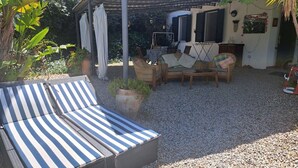 A covered outdoor seating area with striped lounge chairs, wicker furniture, and a small table. - 3 Beautiful hillside holiday rental with sea views and pool (Nuoro)