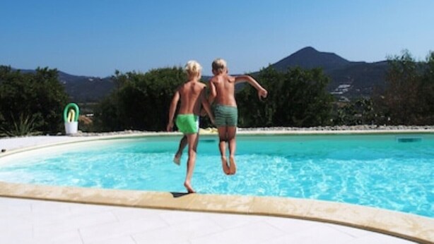 Two people jumping into a swimming pool with a mountain in the background. - 3 Beautiful hillside holiday rental with sea views and pool (Nuoro)