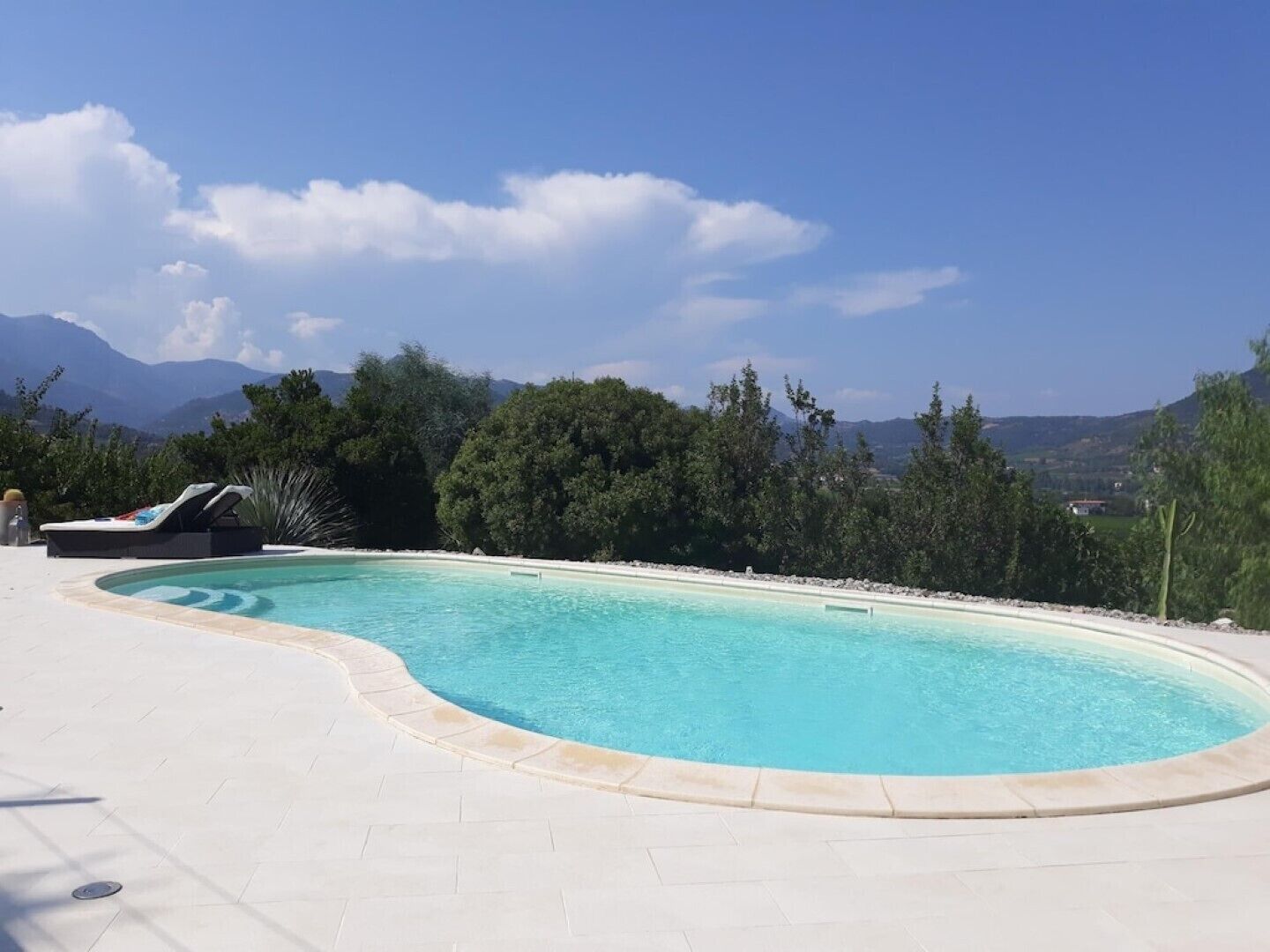 A swimming pool with a curved edge, surrounded by a white tiled deck.