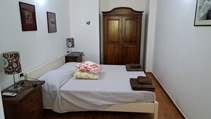 A bedroom with a bed, a nightstand, a lamp, a wardrobe, and two framed pictures on the wall. - 3 Beautiful hillside holiday rental with sea views and pool (Nuoro)