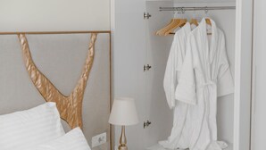 A hotel room with a bed, a bedside lamp, a robe rack with robes, and a wall-mounted towel rack. - Muller Hotel Boutique&Spa (Galati)