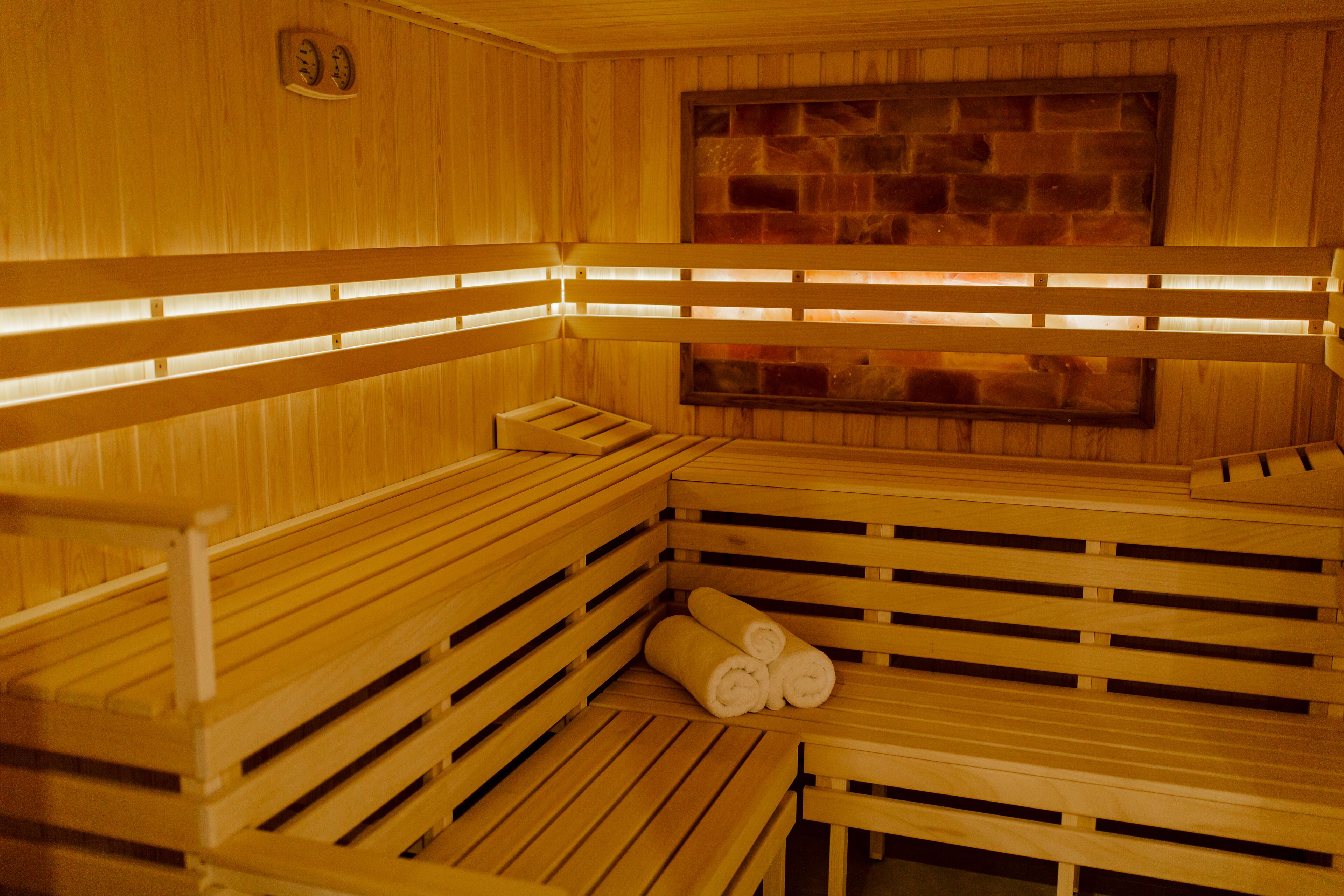A sauna with wooden benches and a stone wall.