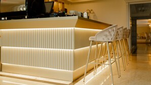 A modern bar area with a counter, bar stools, and a coffee machine. - Muller Hotel Boutique&Spa (Galati)