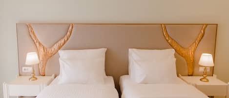 A hotel room with two beds, white bedding, and a large decorative headboard.
