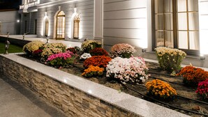 A large, white building with a symmetrical facade, multiple windows, and a well-maintained garden with various flowers. - Muller Hotel Boutique&Spa (Galati)