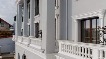 A white building with large columns, balconies, and a covered walkway.
