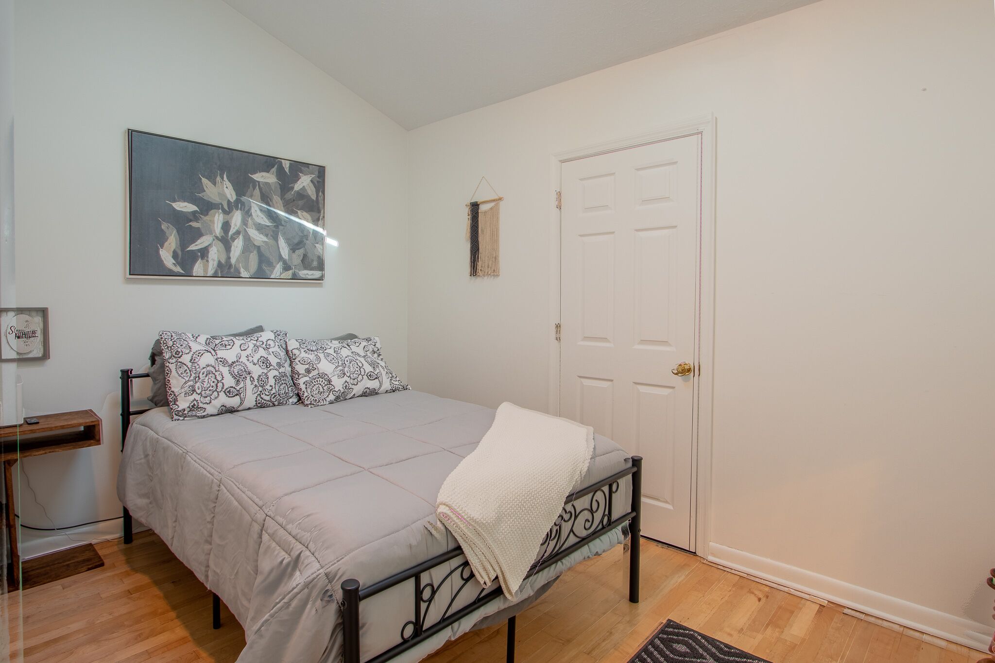 A bedroom with a bed, a door, and a wall-mounted artwork.