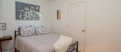 A bedroom with a bed, a door, and a wall-mounted artwork.