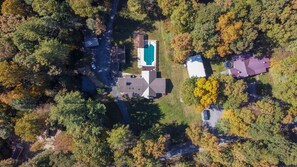 An aerial view of a residential area with a swimming pool, a large house, and a smaller building.
