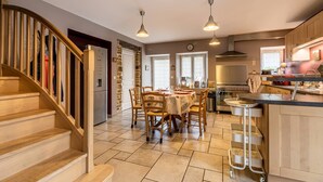 A kitchen with a dining area, wooden staircase, and a view of the outside.