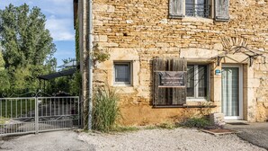 A stone building with a sign for 'Gîte La Vielle Madeleine' and a metal gate.