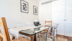 En matplats med ett glasbord, trästolar och inramade konstverk på väggen.