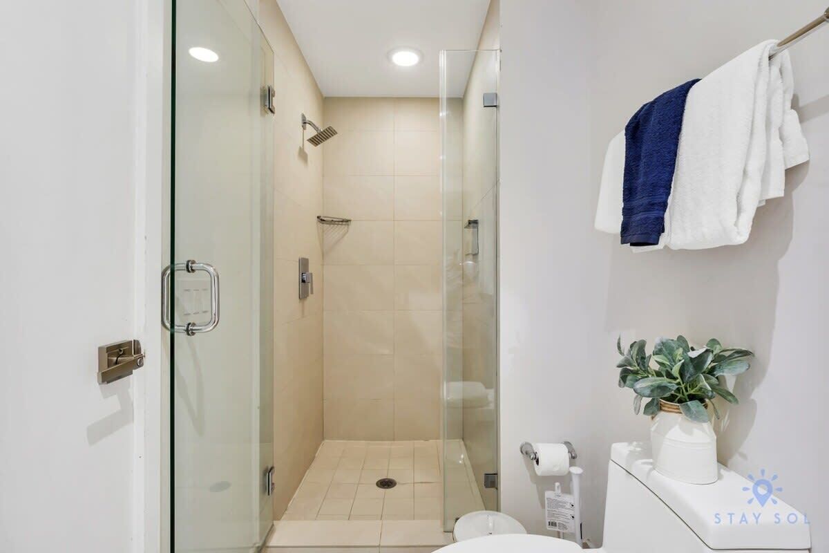 Ein modernes Badezimmer mit einer Duschkabine, Toilette und Waschbecken mit Handtuchhalter.