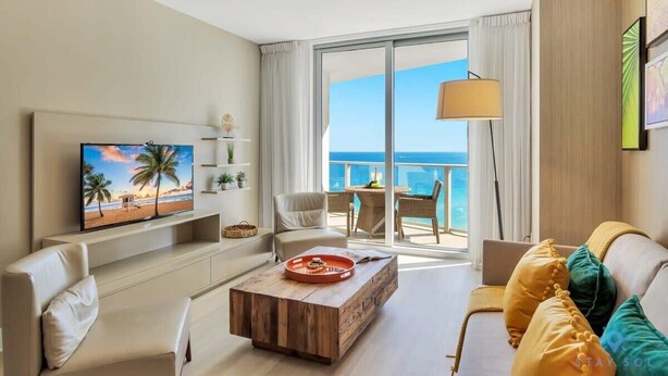 Ein modernes Hotelzimmer mit Balkon und Meerblick, einem Flachbildfernseher und einer gemütlichen Sitzecke.