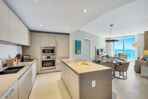 A modern kitchen with stainless steel appliances, a central island, and a dining area with a view of the sea.