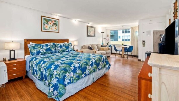 A hotel room with a bed, a desk, a chair, and a sofa.