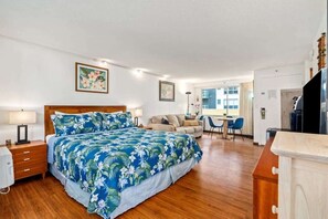 A hotel room with a bed, a desk, a chair, and a sofa.