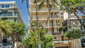 A multi-story hotel with balconies, surrounded by palm trees and other greenery.