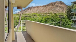 Un balcon avec vue sur une montagne et la verdure.