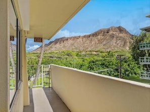 A balcony with a view of a mountain and greenery.