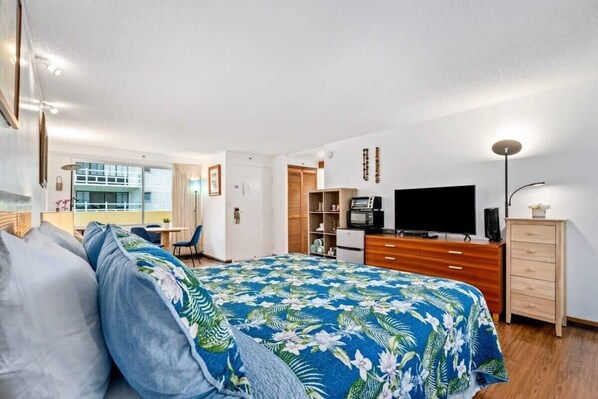 Un dormitorio con cama, escritorio, televisor y armario.