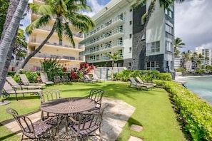 A hotel with a poolside area, outdoor seating, and a view of the ocean.
