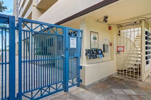 A gated entrance with a blue gate, a security camera, and a sign indicating a secure area.