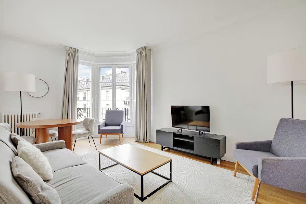 Un salon moderne comprenant un canapé, une table basse, un téléviseur et un coin repas avec une table et des chaises.