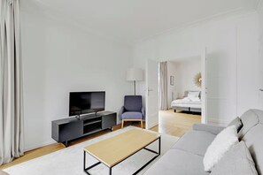 Una sala de estar moderna con un televisor de pantalla plana, un sofá, una mesa de centro y una silla.