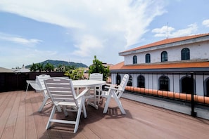 A rooftop terrace with a table and chairs, a view of a building with arched windows, and a mountainous landscape in the background. - w* | Charming 2BR in Casco Antiguo (Panamá)